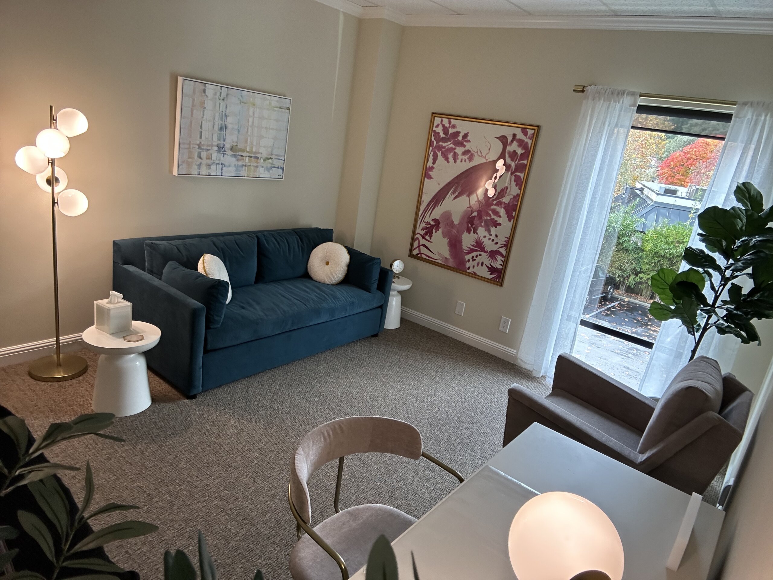 Couples therapy room at Renewed Relationships Counseling Group in Danville CA with teal sofa, pink botanical artwork and natural light
