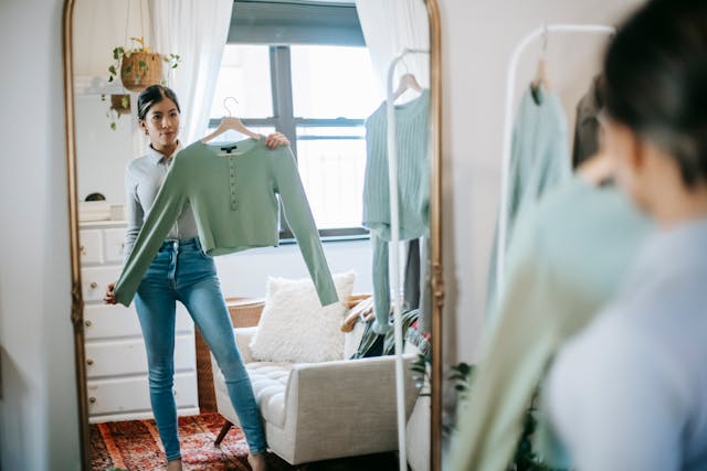 ethnic-female-selecting-and-showing-outfit-in-room
