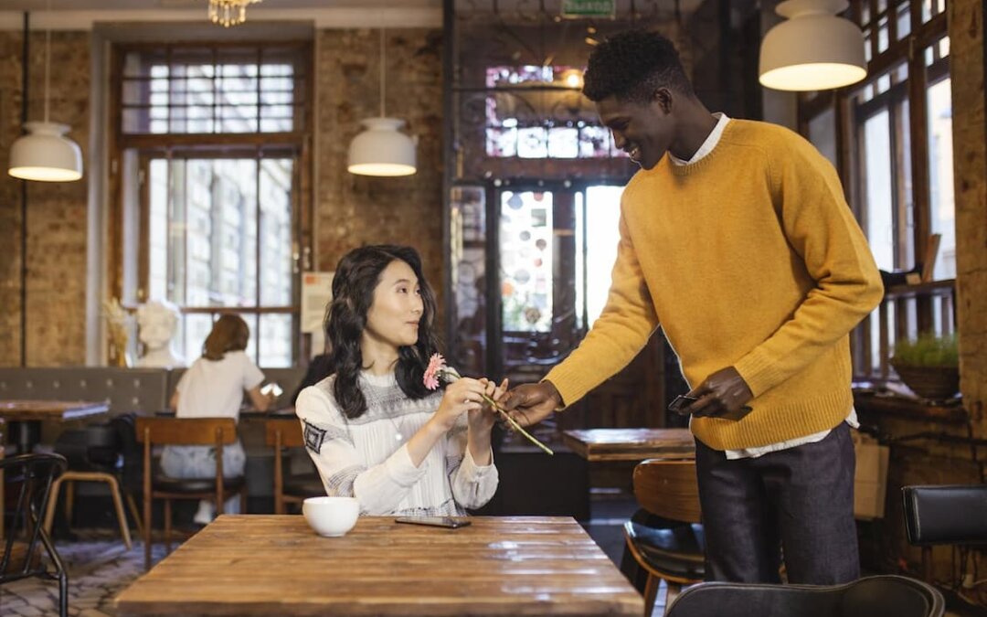 man-giving-a-woman-a-pink-flower-on-a-cafe