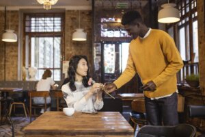 man-giving-a-woman-a-pink-flower-on-a-cafe