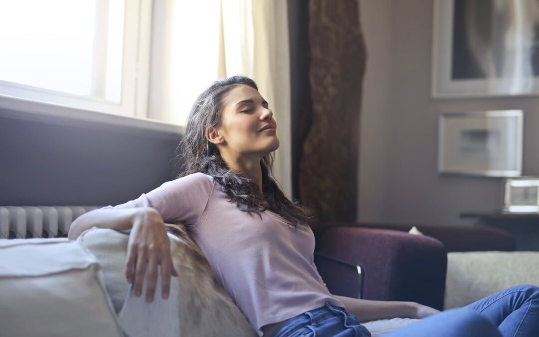 woman-in-pink-long-sleeve-shirt-and-blue-denim-jeans-sitting-on-brown-sofa-with-her-eyes-closed