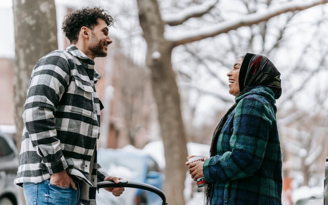 smiling-ethnic-couple-with-stroller-on-sidewalk